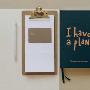 A minimalist office setup featuring a planner, clipboard, card, and pen, perfect for planning and organization.